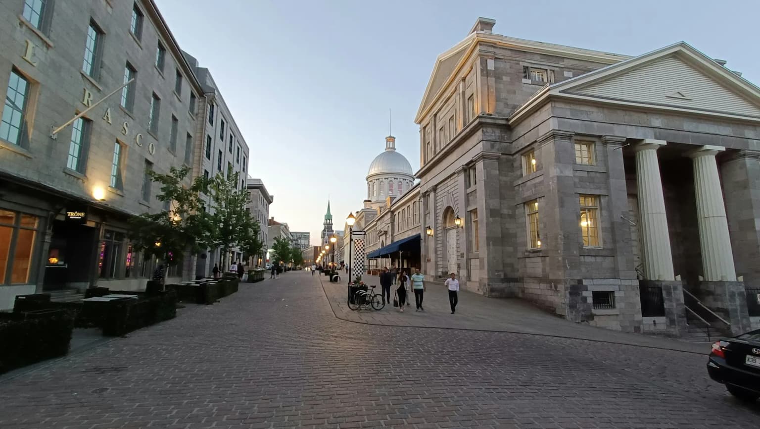 Une rue pavée du Vieux-Montréal, avec le dôme du marché Bonsecours